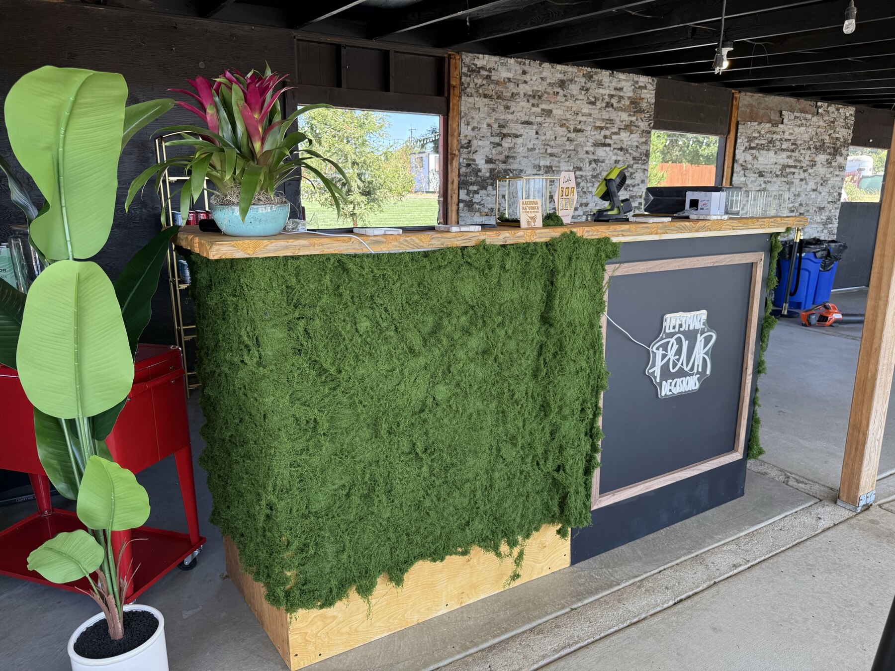 The custom handmade 916 Pour Decisions mobile bar with greenery and branded panels, ready for service.