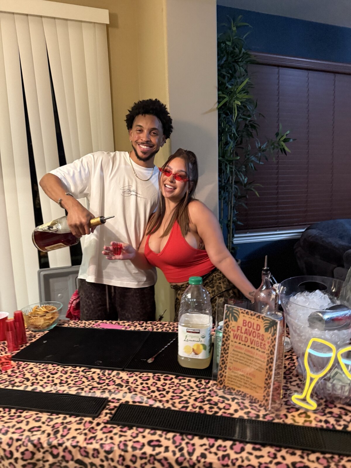 Tyler and Jacque behind their first collapsible bar in a friend’s kitchen, with the leopard-print tablecloth used at the first 916 Pour Decisions event.